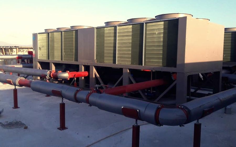 Batterie de groupes froids à condensation par air installée en toiture avec tuyauterie primaire calorifugée